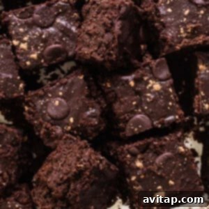 A pile of paleo pumpkin brownies on a white plate, showcasing their rich, dark color and dense texture.