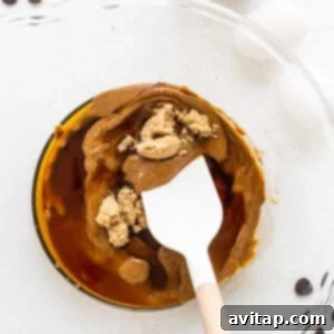 A pancake-like mixture with a spoon in it on a plate, representing the creamy wet ingredients.