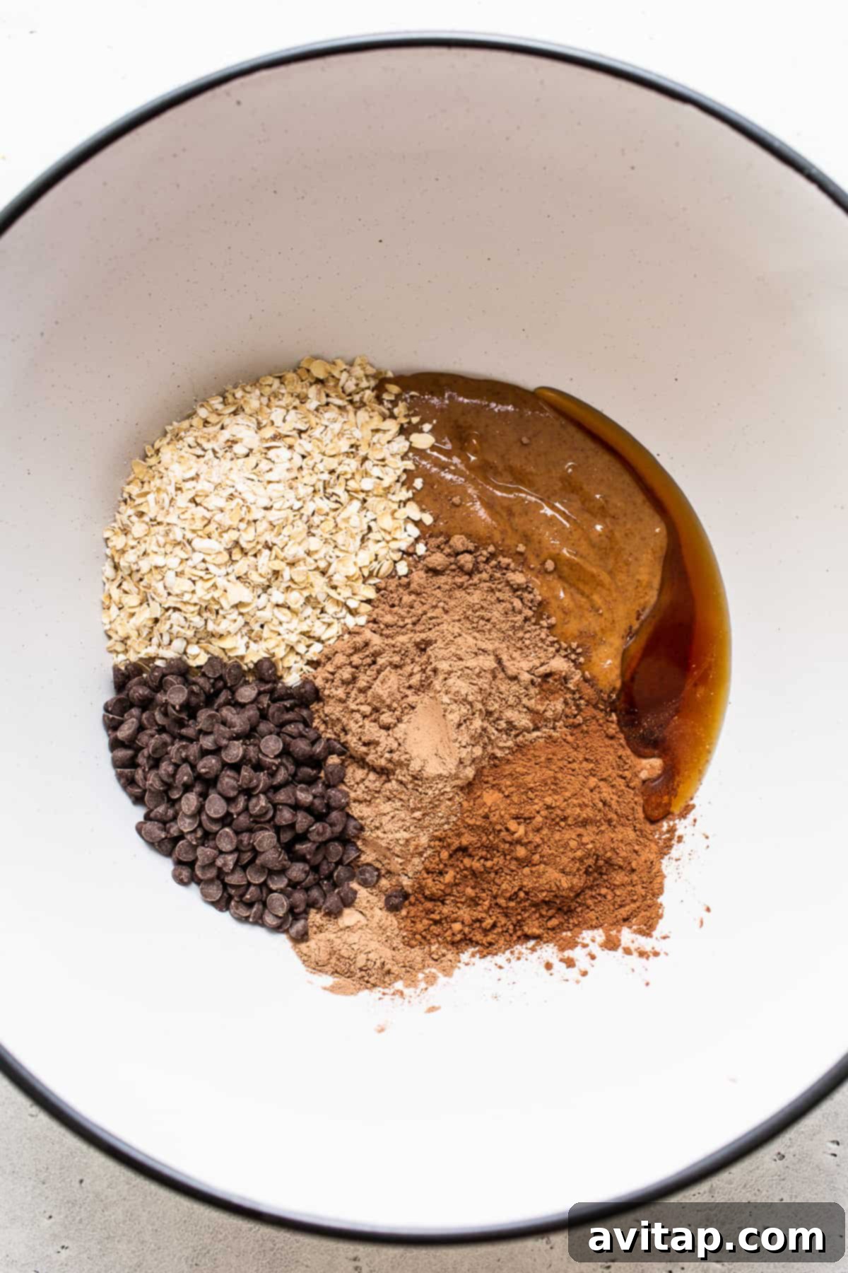 Bowl of ingredients for Mint Chip Protein Balls, including oats, cocoa, and chocolate chips.