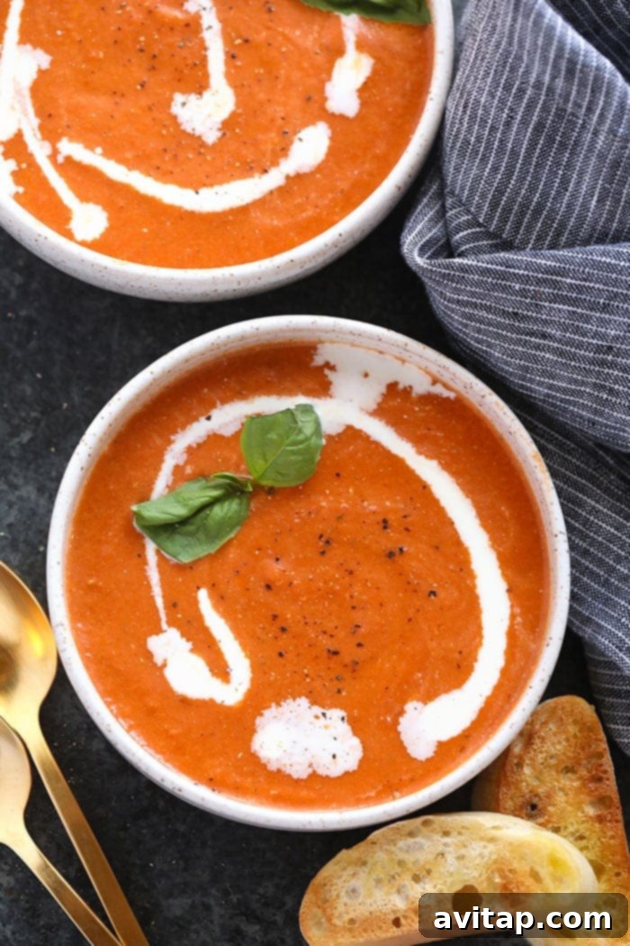 Quick & Healthy Tomato Bisque Soup with Greek Yogurt and Basil Two bowls of creamy tomato bisque soup, garnished with a swirl of cream and fresh basil leaves, ready to be served as a comforting meal.
