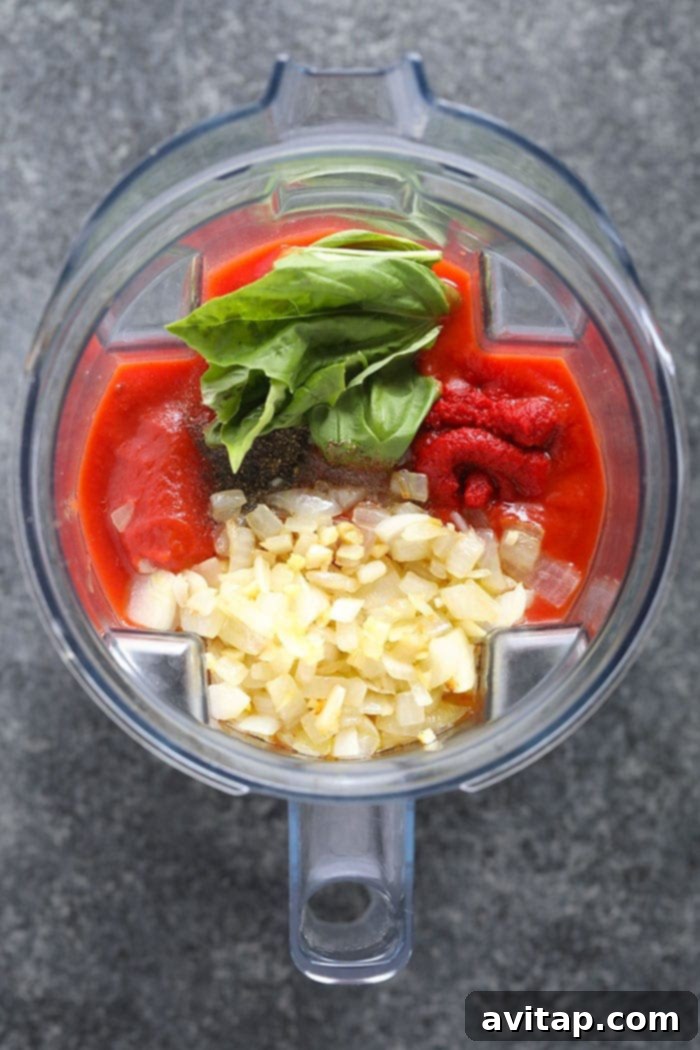 Blending for Perfection: Crafting Your Creamy Tomato Bisque Base Canned tomatoes, fresh basil, and other bisque ingredients are being added to a high-speed blender, ready to be pureed into a smooth soup base.