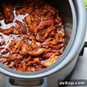 A slow cooker full of honey sriracha pulled chicken.