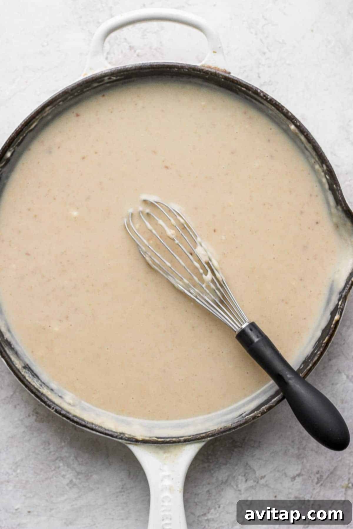 A cast iron skillet containing a rich, creamy bacon roux, ready to be poured over the green beans.