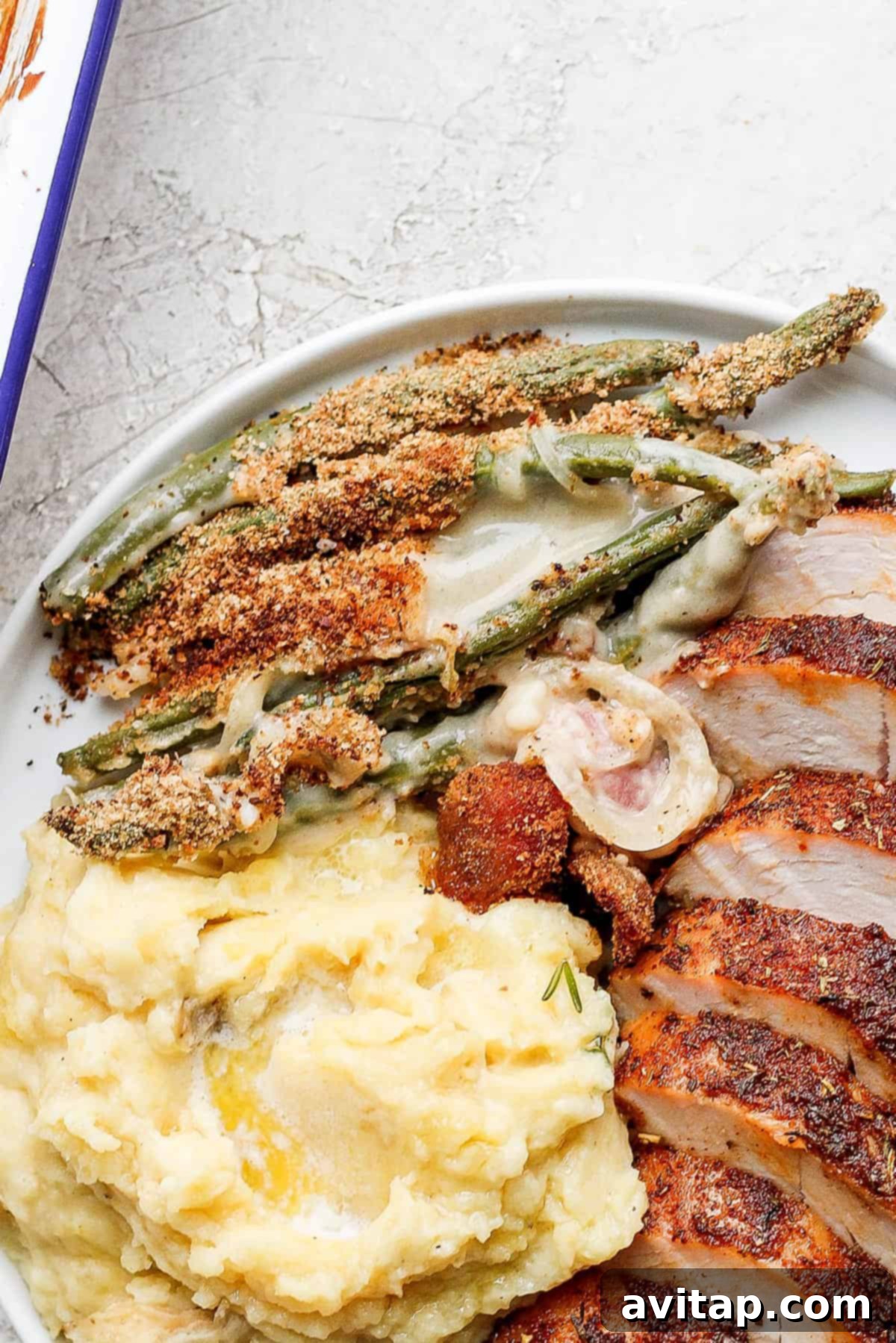 A festive Thanksgiving plate featuring a generous serving of green bean casserole with bacon alongside other holiday dishes.