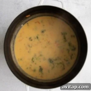 Broccoli cheddar soup in the pot, with cheese melted in, showing its creamy texture.