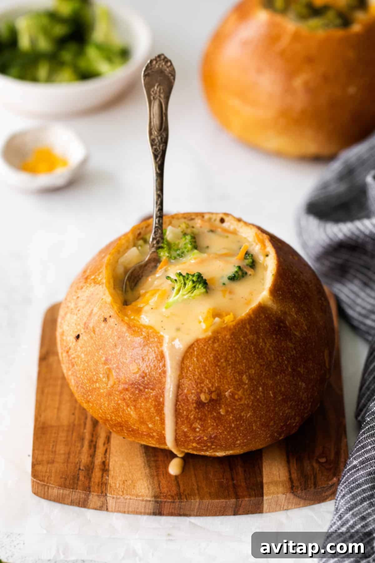 A steaming bowl of Panera-style broccoli cheddar soup nestled within a golden bread bowl, ready for enjoyment.