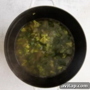 Cooking broccoli with onions in a large pot for the soup base.