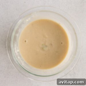 A smooth flour and broth roux being prepared in a bowl.