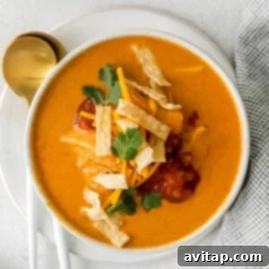 a bowl of mexican chicken soup with tortillas and sour cream.