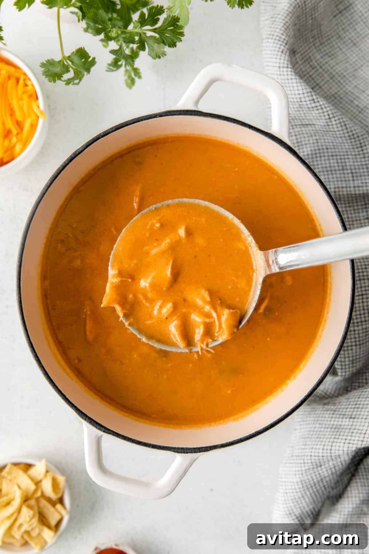 Chilis Hearty Chicken Enchilada Soup 4 A ladle scooping rich, thick chicken enchilada soup from a pot, showcasing its creamy texture.