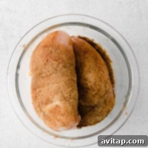 two pieces of chicken in a glass bowl on a white surface.