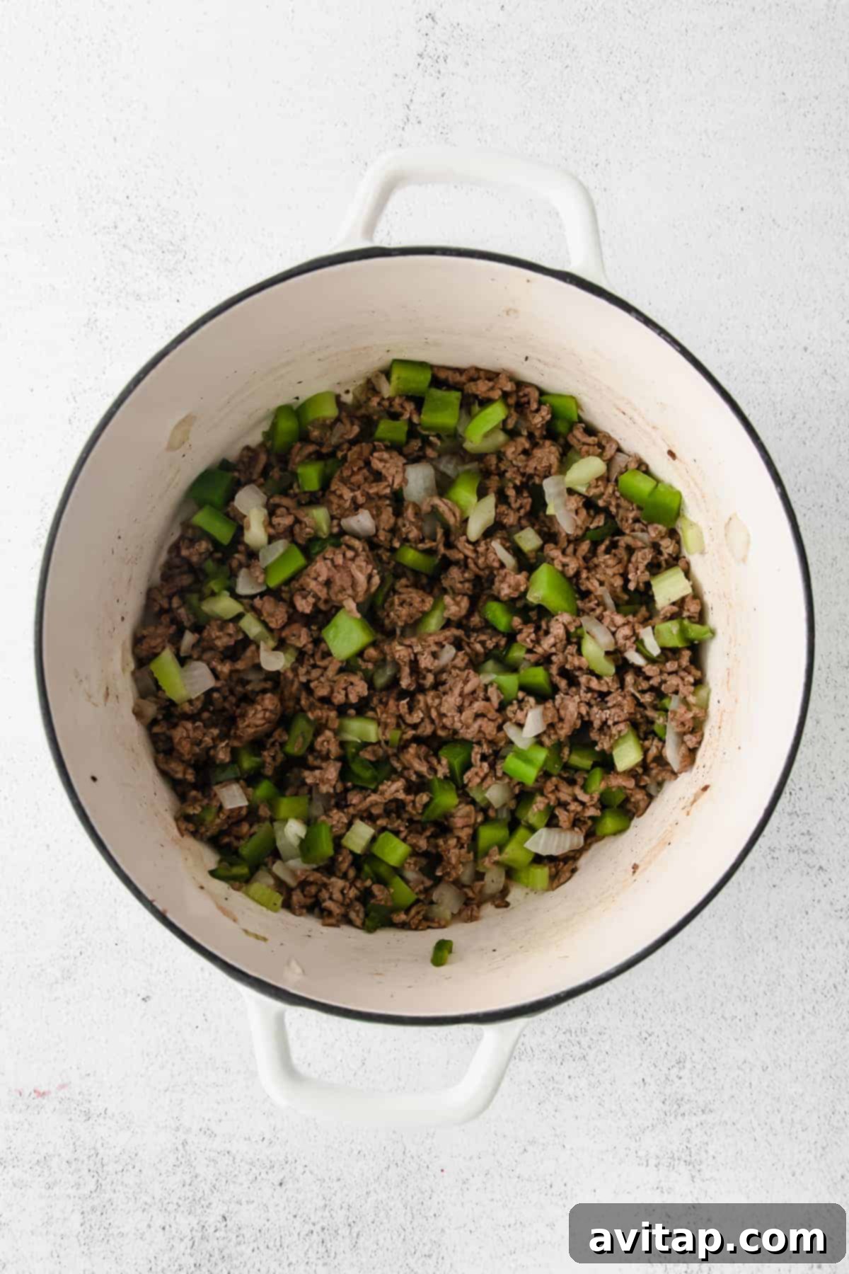 Close-up of ground beef browning in a Dutch oven, an essential first step for building flavor in chili.