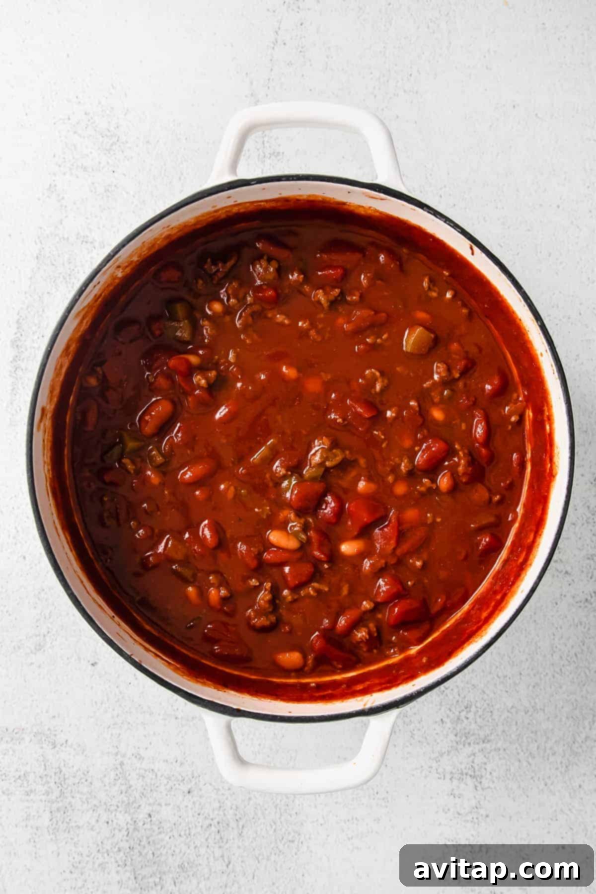 A large pot of rich, simmering chili on the stovetop, showcasing its hearty texture.