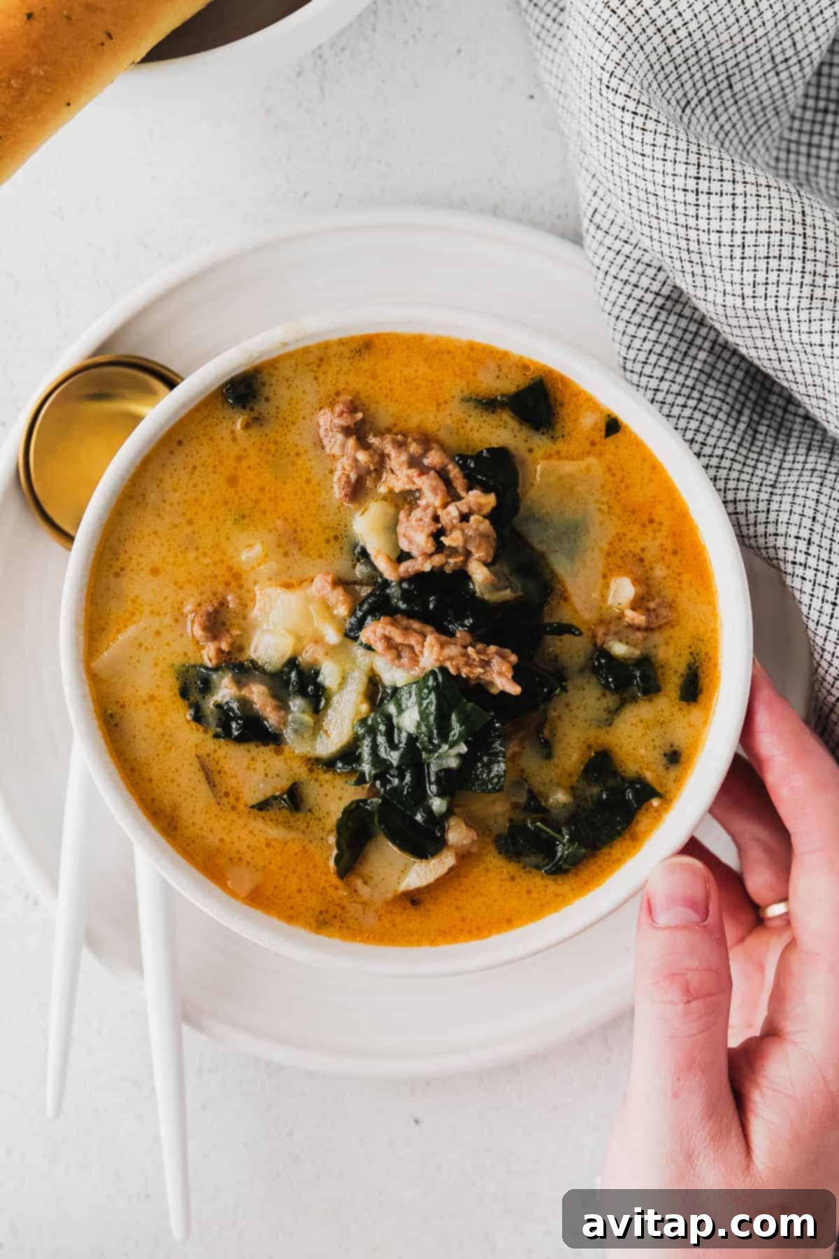 A steaming bowl of homemade Zuppa Toscana soup, garnished with fresh parsley and a side of crusty bread, ready to be enjoyed.