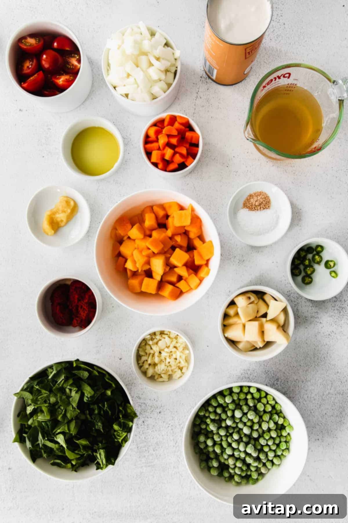 Assortment of fresh ingredients for pumpkin curry laid out on a kitchen counter, showcasing vibrant vegetables and spices.