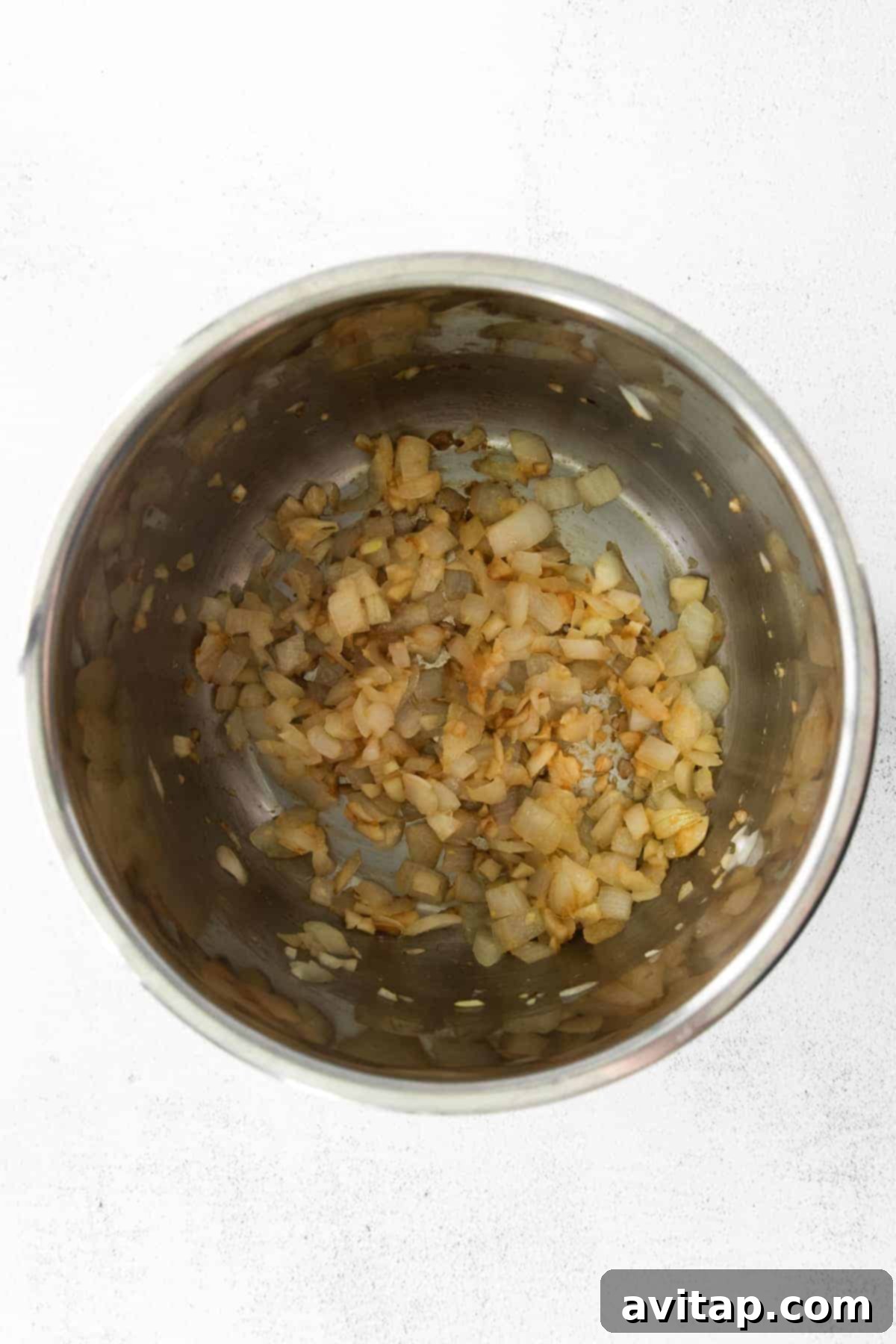 Onions being sautéed in an Instant Pot, forming the aromatic base for a delicious curry.