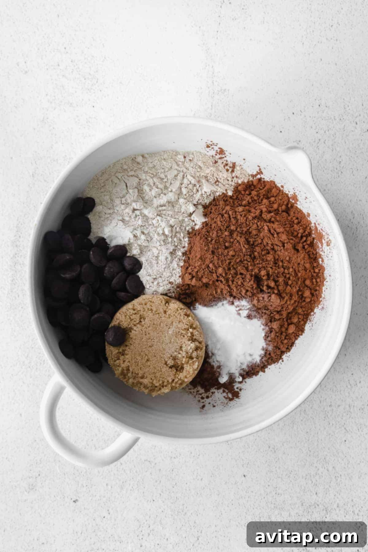 Dry ingredients for pumpkin bread, including flour, sugar, and cocoa powder, mixed in a large bowl.