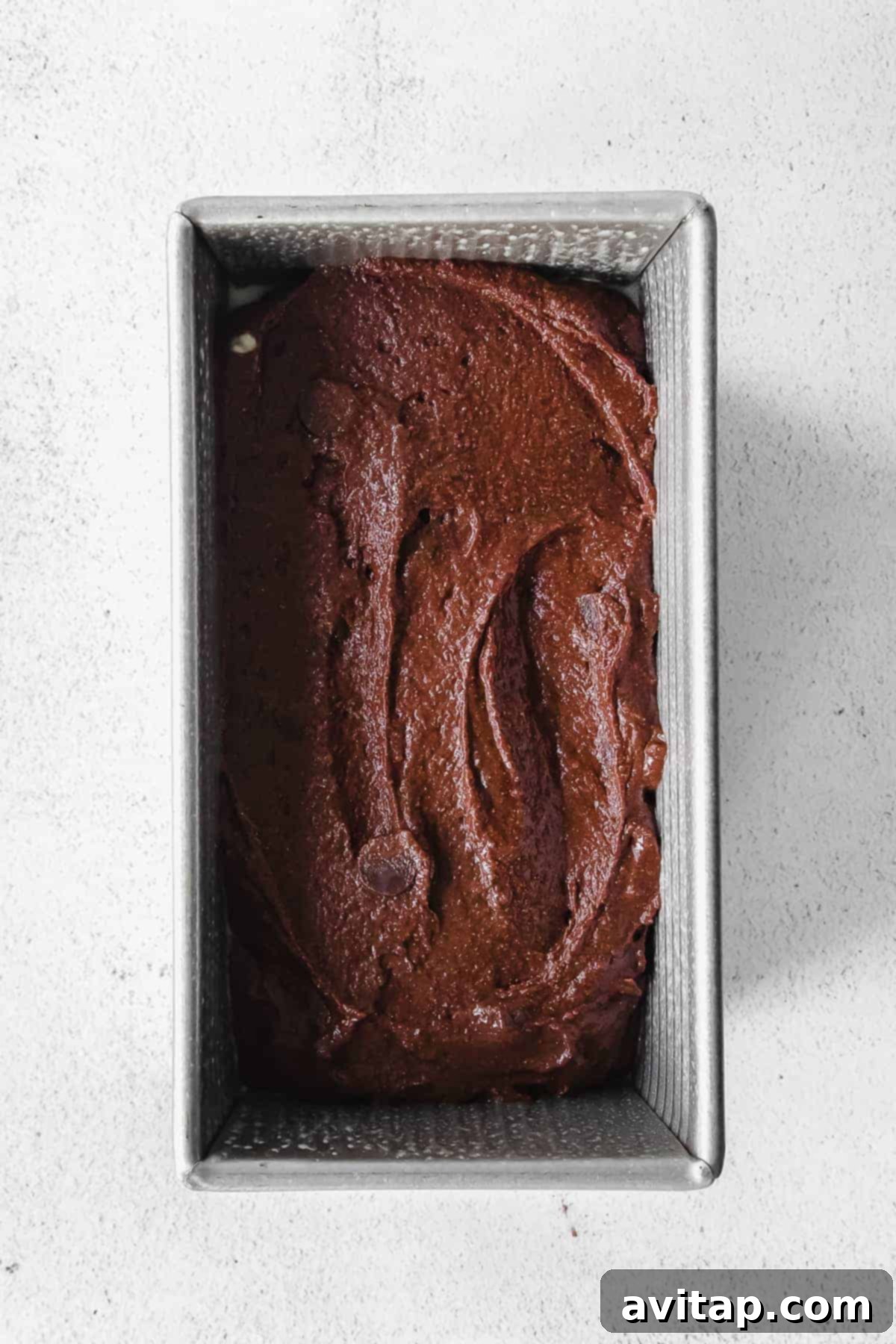 Thick, rich chocolate pumpkin bread batter in a loaf pan, ready for the oven.