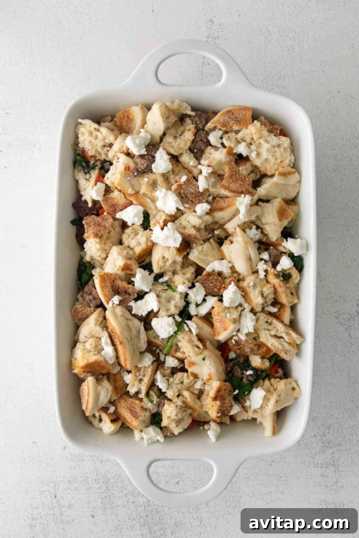 Prepared breakfast bake ingredients meticulously arranged in a casserole dish before baking.