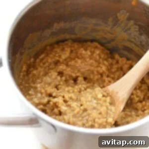 Oatmeal cooked in a pan with a wooden spoon.