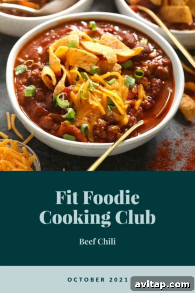 A steaming bowl of classic beef chili, generously topped with shredded cheddar cheese, ready to be enjoyed.