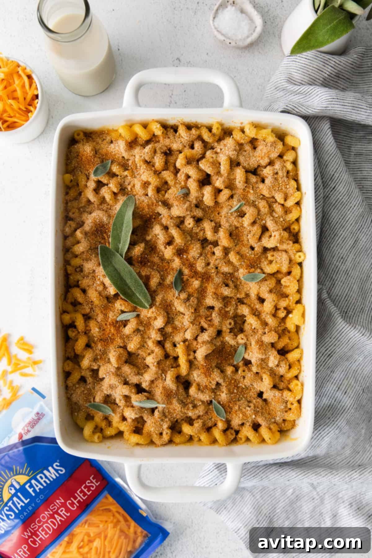 Golden-brown butternut squash mac and cheese in a casserole dish, garnished with fresh sage leaves.