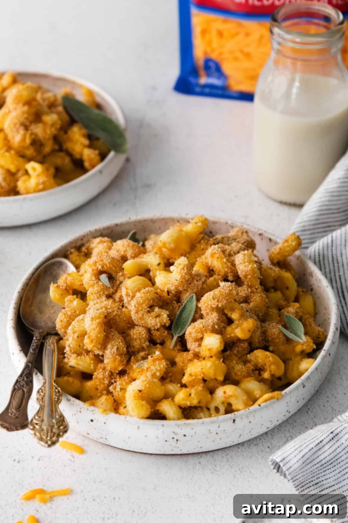 A serving of butternut squash mac and cheese in a bowl, topped with fresh sage, ready to be enjoyed.
