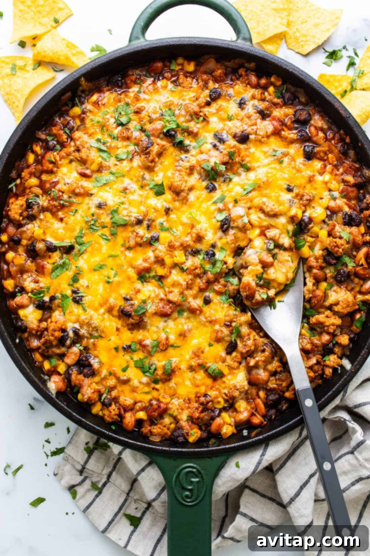 A skillet of baked cheesy chili with a side of tortilla chips.
