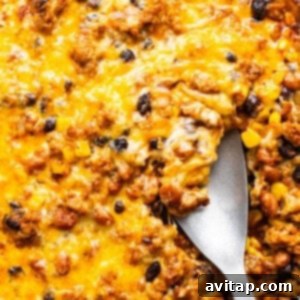 A skillet with baked cheesy casserole containing ground meat, black beans, and corn.