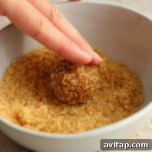 A person putting turbinado sugar into a bowl, preparing to coat cookie dough balls.