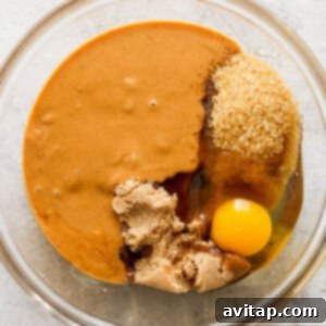 A bowl with an egg and a spoon in it, ready for mixing peanut butter cookie dough.