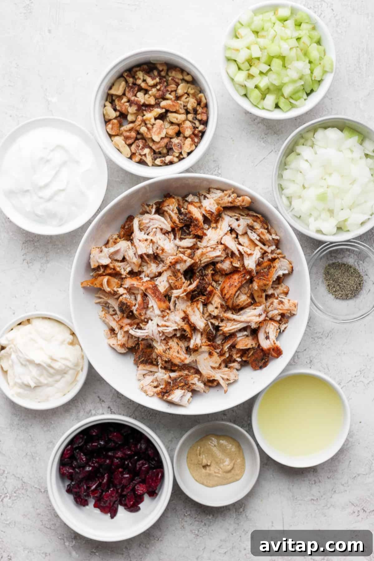 A large mixing bowl filled with all the fresh ingredients for a delightful turkey salad, poised for mixing.