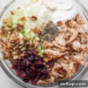 Mixing diced celery, dried cranberries, and chopped walnuts into the creamy turkey salad base.