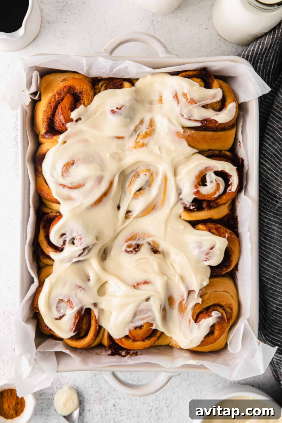 maple cinnamon rolls with a cream cheese frosting in a baking dish, freshly baked