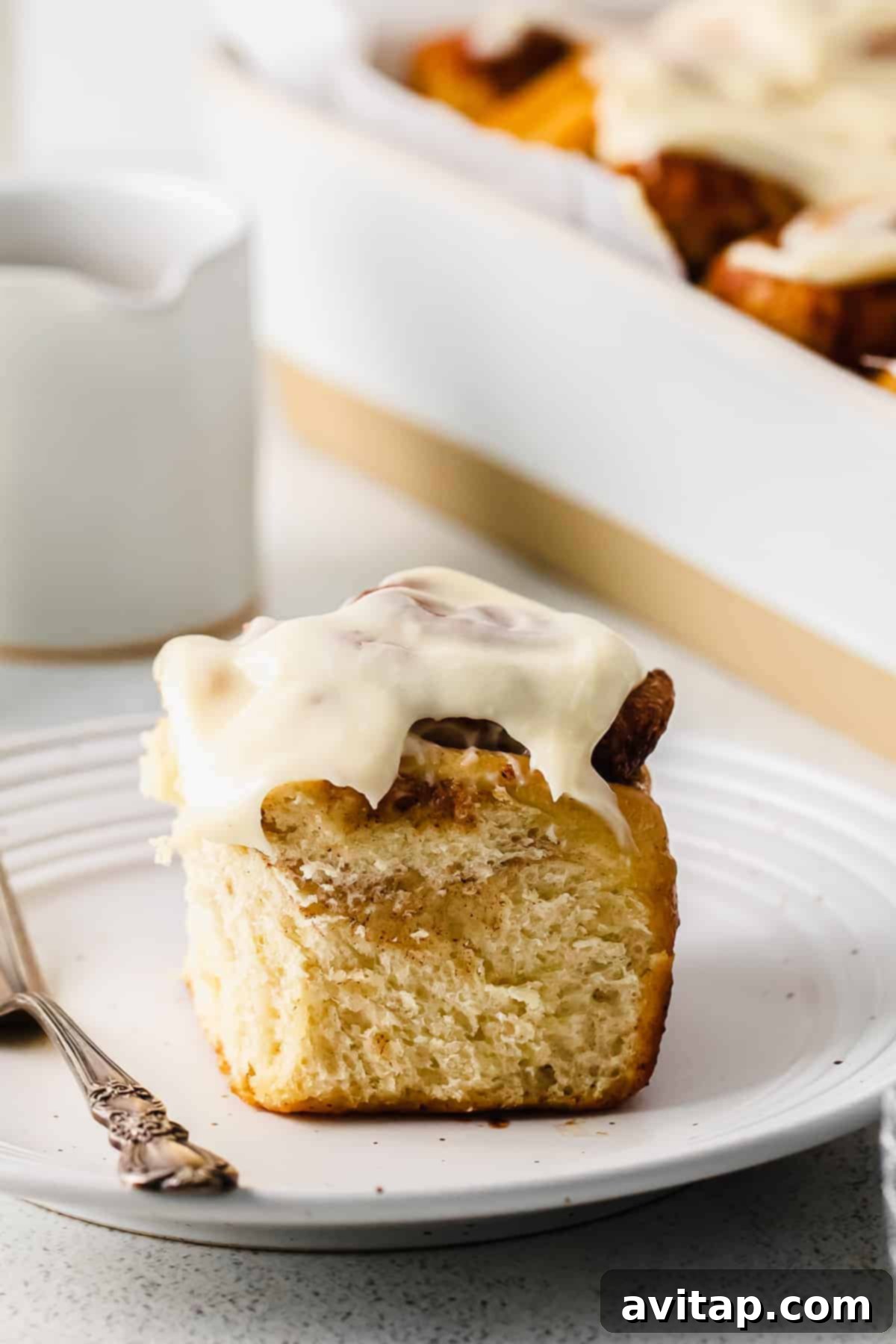 single maple cinnamon roll on a white plate