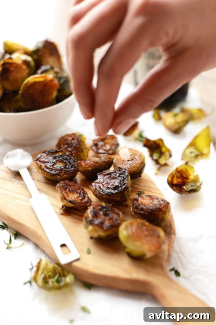 Crispy roasted Brussels sprouts generously sprinkled with flaky sea salt, highlighting their golden-brown edges and vibrant green color.
