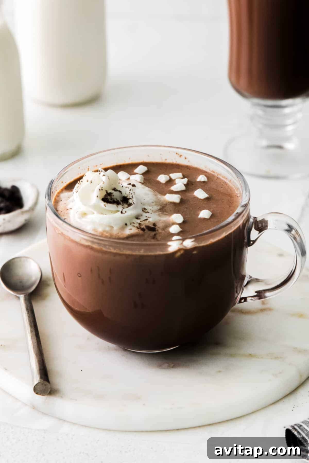Steaming mug of homemade Maple Sea Salt Hot Chocolate, garnished with whipped cream and a sprinkle of sea salt