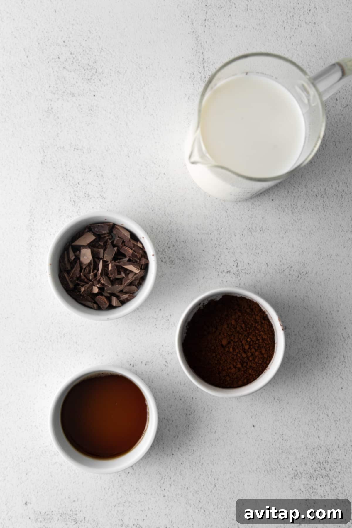 Close-up of the ingredients laid out for Maple Sea Salt Hot Chocolate, including dark chocolate, maple syrup, cocoa powder, and milk.