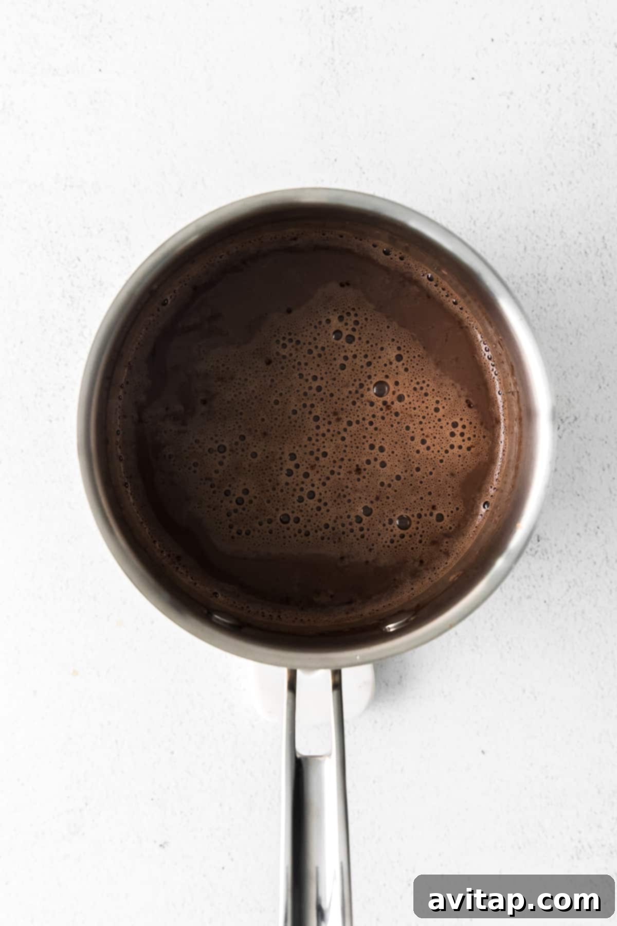 Saucepan on a stovetop with Maple Sea Salt Hot Chocolate being whisked, ready in minutes.