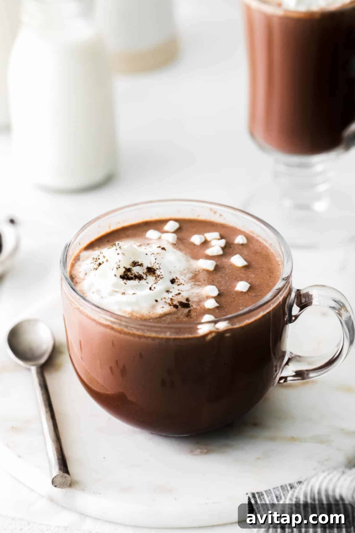 Mugs of hot chocolate topped with mini marshmallows and whipped cream.