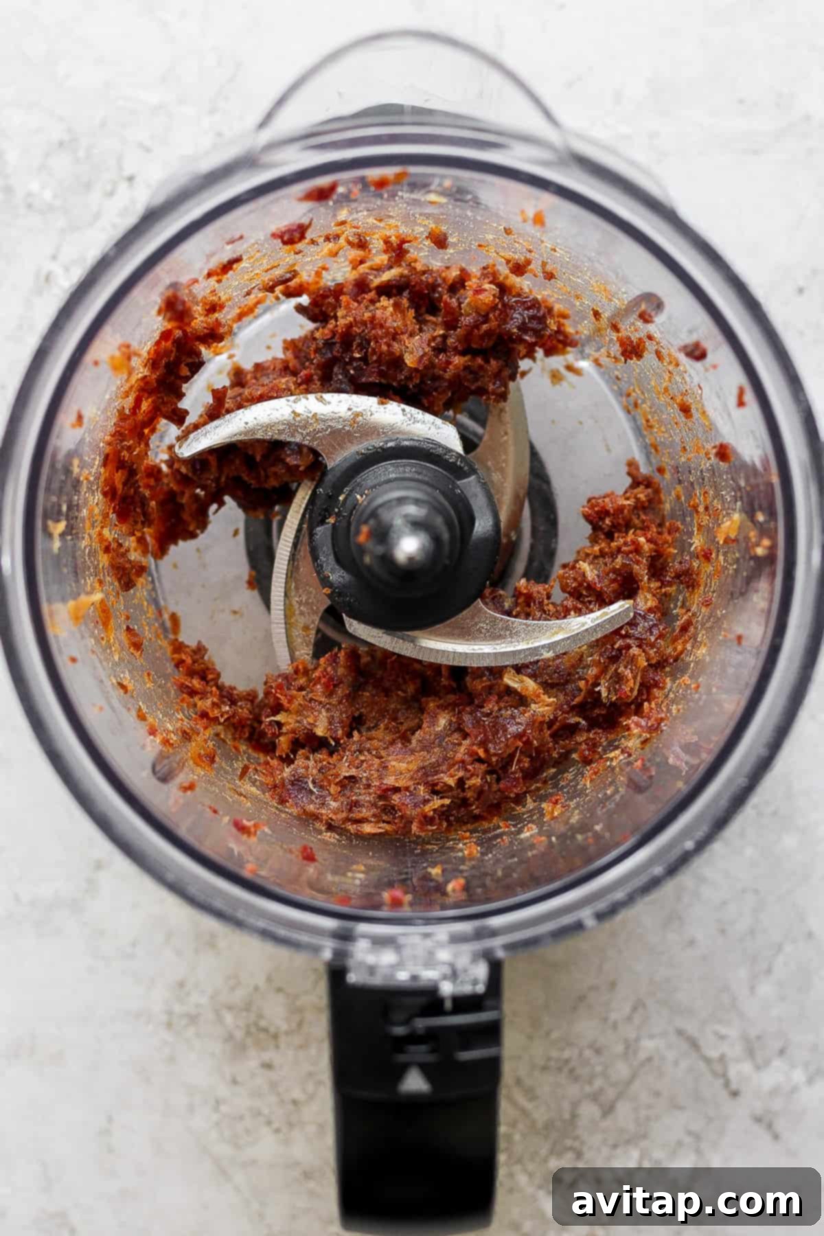 A high-speed food processor filled with pitted Medjool dates, in the process of being blended into a smooth, sticky date caramel paste.