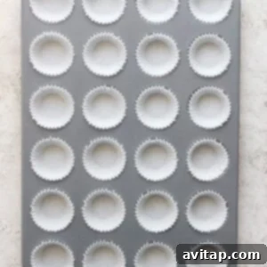 A mini muffin tin partially filled with cupcake liners, meticulously arranged and ready for the salted caramel date cups mixture.