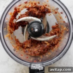 Medjool dates being processed into a thick, sticky, and smooth caramel-like paste in a food processor, ready to be shaped.