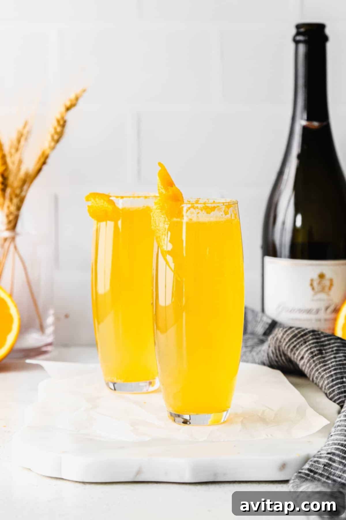 Two mimosas in stemless champagne flutes, showcasing a simple yet elegant brunch cocktail, ready to be enjoyed.