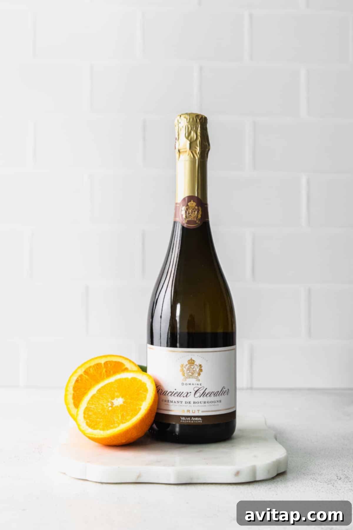 A bottle of sparkling wine next to fresh orange slices, highlighting the two main ingredients of a perfect mimosa, set for a delightful brunch.