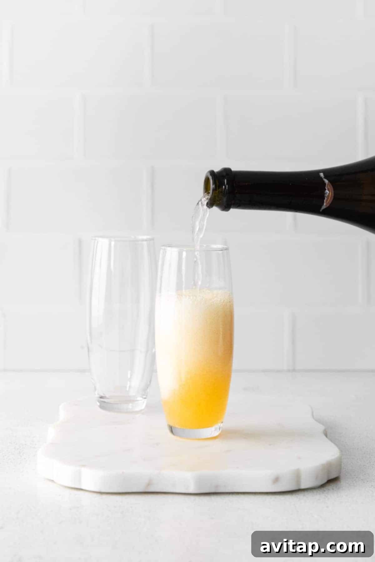 Effervescent champagne being poured into a glass already containing orange juice, creating a classic mimosa with a beautiful fizz.