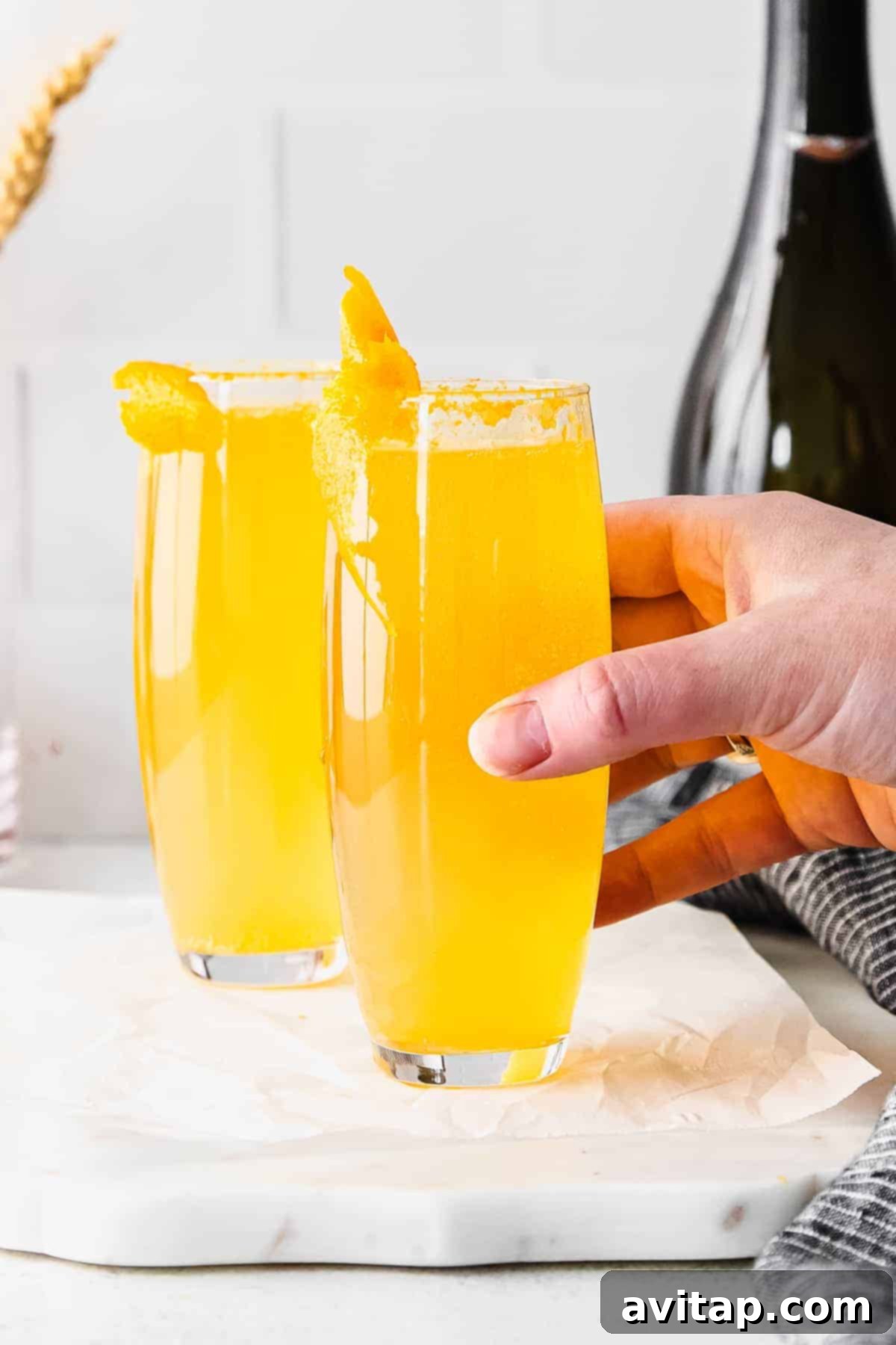 A classic mimosa served in a modern stemless champagne flute, beautifully garnished with an orange slice, ready for a delightful brunch.