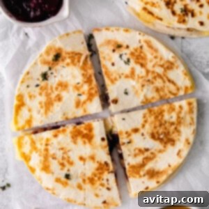 Leftover Thanksgiving turkey quesadilla topped with cranberry chutney on a white plate.