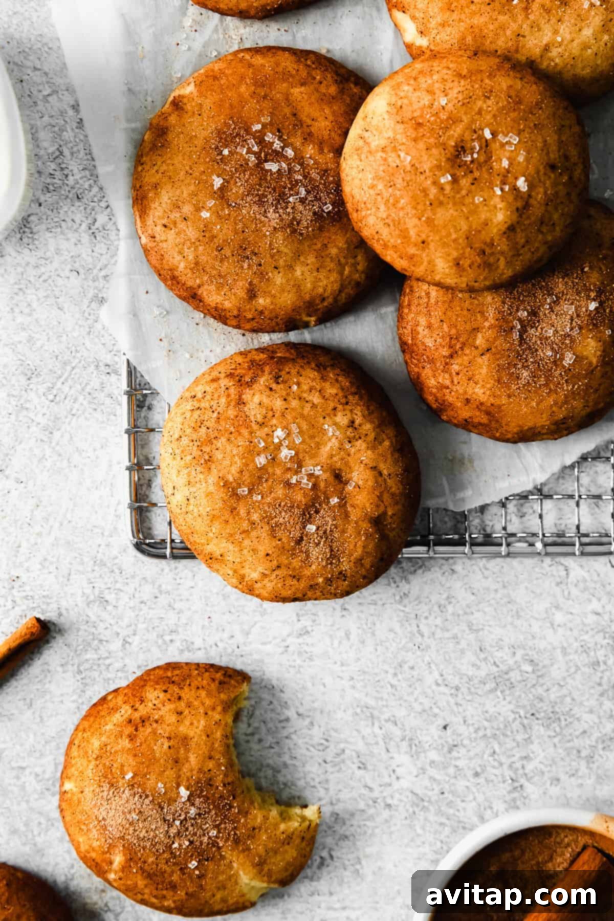 Baked snickerdoodles on a wire rack, showcasing their crinkly tops and cinnamon-sugar coating.