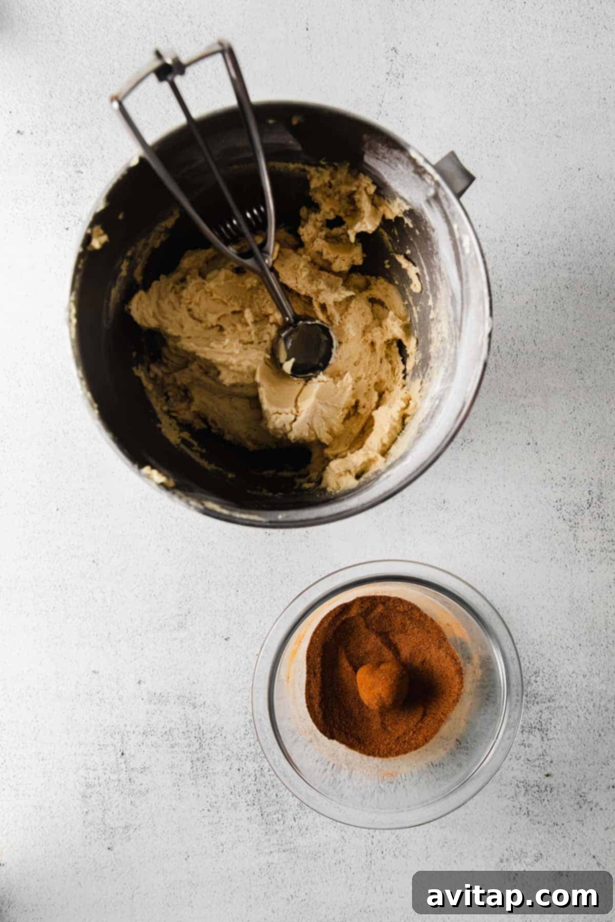 Snickerdoodle cookie dough in a bowl, with a cookie scoop ready to portion the dough.